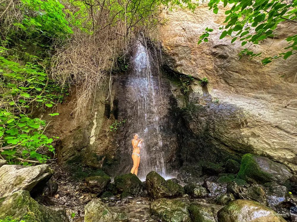 Mae standing under a Waterfall in Cahorros de Monachil in summer.