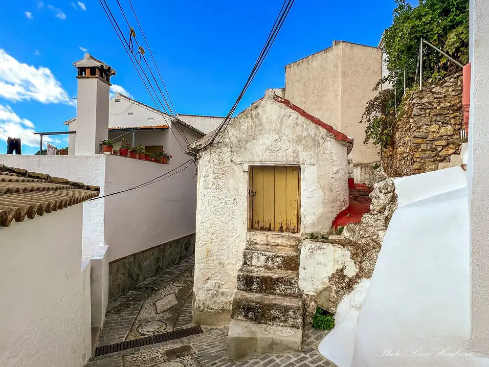 Igualeja narrow street past a small shed with stairs.