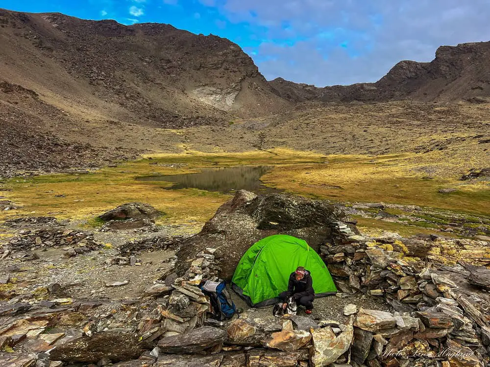 Ma and Atlas sitting outside the tent in Siete Lagunas surrounded by meadows and mountains.
