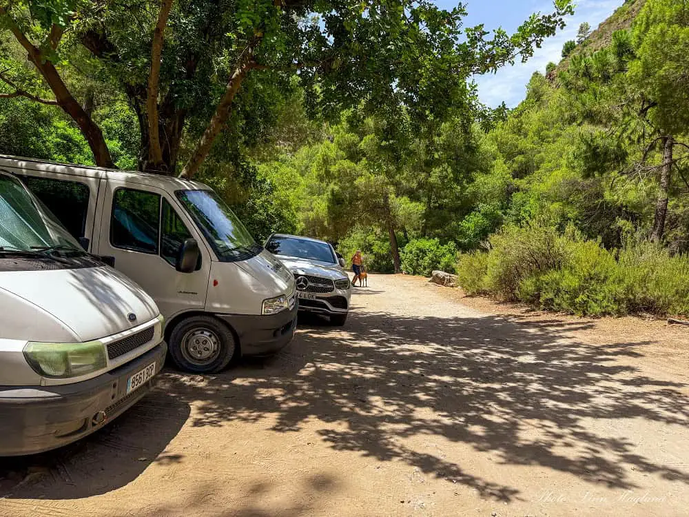 Vans parked on the right side of a dirt track at the parking for Rio Verde Otívar hike.